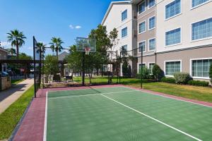 - un court de tennis en face d'un bâtiment avec un panier de basket dans l'établissement Residence Inn Beaumont, à Beaumont