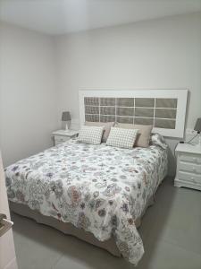 a white bedroom with a large bed and two night stands at Marea apartamento. in Adra