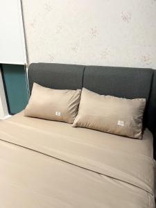 a bed with two pillows on top of it at H2O Residences Ara Damansara PJ with WiFi Washing Machine and Dryer in Petaling Jaya