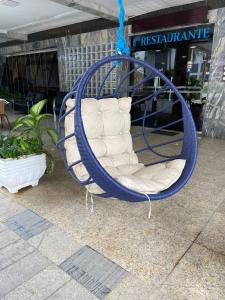 um baloiço azul com uma cadeira branca em frente a uma loja em Hotel Palace em Cachoeiras de Macacu