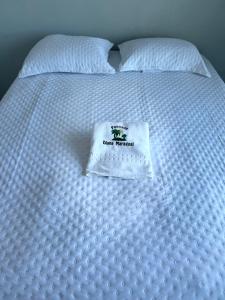 a white bed with a white comforter with a sign on it at Pousada Diana Maragogi in Maragogi