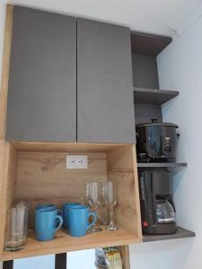 un meuble avec des tasses et des verres sur une étagère dans l'établissement Linda Suite minimalista, à Guayaquil