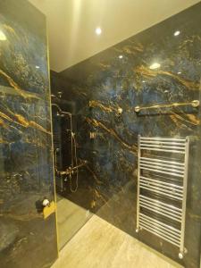 La salle de bains est pourvue d'une douche et d'un mur en marbre noir. dans l'établissement شقة فخمة باطلالة جذابة, à Irbid