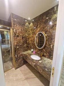 La salle de bains en marbre est pourvue d'un lavabo et d'un miroir. dans l'établissement شقة فخمة باطلالة جذابة, à Irbid
