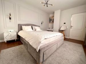a bedroom with a large bed with white sheets and a rug at Ghinda Nest in Bistriţa