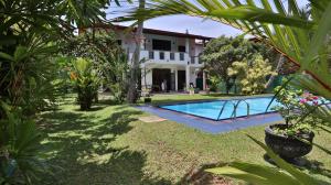 a garden with a swimming pool in front of a house at Villa Riverplace in Beruwala