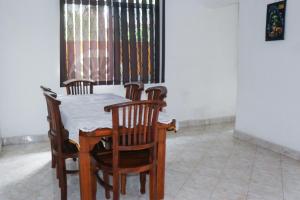 a dining room table with four chairs and a window at Villa Mare in Wadduwa