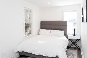 a white bedroom with a large bed and a window at Alexander Beach House Okanagan in Penticton