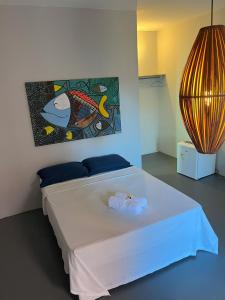 a bedroom with a white bed with a painting on the wall at Pousada Villa Xaréu in Barra Grande