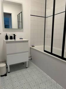 uma casa de banho com uma banheira e um lavatório e uma banheira em Jolie cosy appartement de 52m2 em Asnières-sur-Seine