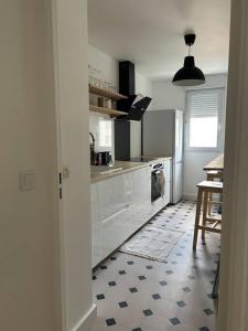 uma cozinha com armários brancos e um piso preto e branco em Jolie cosy appartement de 52m2 em Asnières-sur-Seine