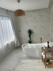 a white bathroom with a tub and a window at Al ATLAL apartment in Nizwa