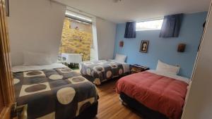 Duas camas num quarto com paredes azuis em Ccapac Inka Ollanta em Ollantaytambo