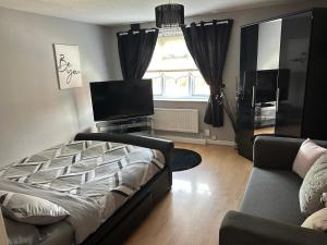 een woonkamer met een bed, een bank en een televisie bij 2 bedroom house close to city centre with gated driveway in Liverpool