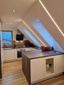 an attic kitchen with white cabinets and a large window at Ferienwohnung HELISA in Hart im Zillertal