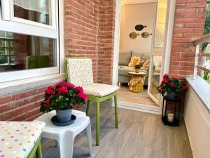 eine Veranda mit 2 Stühlen und einem Tisch mit Blumen in der Unterkunft Apartamento VERDEMAR SUANCES, con parking, piscinas y pádel in Suances