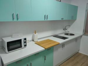a white kitchen with a microwave and a sink at Vivienda Turística Bufer Cazorla in Cazorla