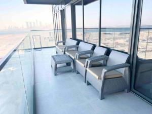 Un balcón con sillas y mesas en un edificio. en Panoramic Luxury Apartment, en Abu Dabi