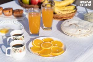 a table with oranges and cups of coffee and juice at StayVista at Ava - The Country House with Breakfast & Miniature Golf in Mysore