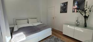 Un dormitorio blanco con una cama y un jarrón de flores en Stilvolle Ferienwohnung Dresden, en Dresden