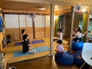 a group of people sitting in a yoga class at 奄美ゲストハウス HUB a nice INN in Setouchi
