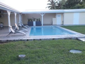 a swimming pool with two chairs and a house at Villa Créoléna in Anse-Bertrand