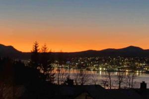 a sunset over a city and a body of water at Fin leilighet i Tromsø in Tromsø