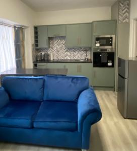Ground floor apartment Brean في برين: أريكة زرقاء في غرفة المعيشة مع مطبخ
