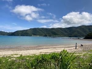 a person standing on a beach near the water at 一棟貸しの移住案内古民家　itoma in Setouchi