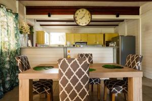 eine Küche mit einem Holztisch und einer Uhr an der Wand in der Unterkunft villa La Mérédith in Le Lamentin