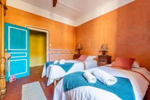 two beds in a room with orange walls at Casa Antoinette-Invitation vintage au-dessus du Vieux-Port in La Ciotat
