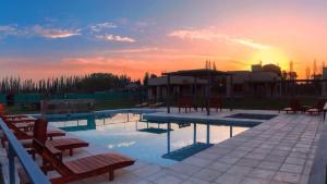 a pool with chairs and a sunset in the background at Buenas Tierras Cabañas in San Rafael