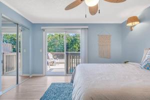 um quarto com paredes azuis e uma cama com uma ventoinha de tecto em Beachside Duplex off Flagler with FREE garage parking em New Smyrna Beach