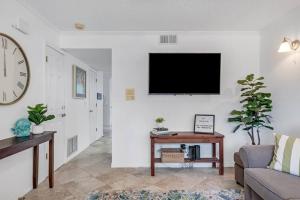 uma sala de estar com um sofá e uma televisão na parede em Beachside Duplex off Flagler with FREE garage parking em New Smyrna Beach