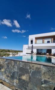 une villa avec une piscine en face d'une maison dans l'établissement Splendide maison de campagne avec piscine et vue panoramique., à El Maamoura