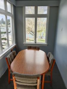 uma mesa de madeira num quarto com duas janelas em Lakeside Backpackers em Queenstown