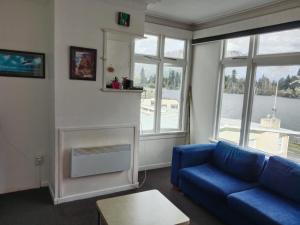 a living room with a blue couch and a fireplace at Lakeside Backpackers in Queenstown