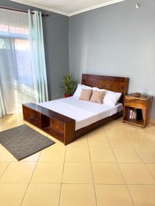 1 dormitorio con 1 cama grande con marco de madera en Sally's home-near JNIA airport, en Dar es Salaam