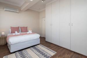 een witte slaapkamer met een groot bed met roze kussens bij Two bedroom Apartment on kloof in Kaapstad