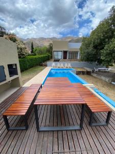 a wooden deck with a table and a swimming pool at Andelka-Chumamaya Merlo San Luis in Merlo