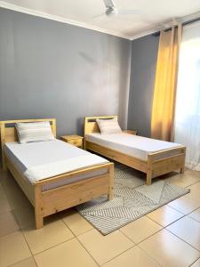 2 camas individuales en una habitación con ventana en Sally's home-near JNIA airport, en Dar es Salaam