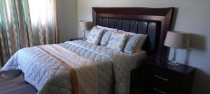 a bedroom with a large bed with a wooden headboard at Qunu Heritage Home - Mthatha in Mthatha