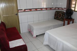 Cette chambre comprend deux lits et un fauteuil rouge. dans l'établissement Edifício Guarani, à Goiânia