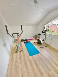 L’appartement du Fayé avec jacuzzi privé في Étueffont-Bas: صالة ألعاب رياضية مع جهازي ركض ودراجات ممارسة الرياضة