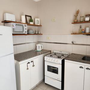 Il comprend une cuisine blanche équipée d'une cuisinière et d'un four micro-ondes. dans l'établissement Vintage, à La Plata 3 autres photos