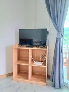 TV en un soporte de madera con ventana en บังกะโลบ้านสวนเอก Bungalow Baan Suan Aek, 