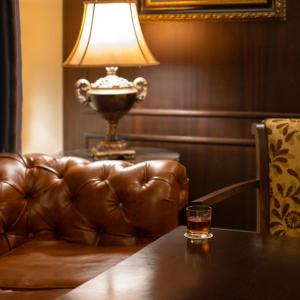 a glass on a table with a couch and a lamp at Le Cedrus Hotel in Al Arz