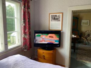 einen Fernseher auf einer Kommode in einem Schlafzimmer in der Unterkunft Little Guesthouse Cabin, Once Home to Lotta Svärd in Raasepori