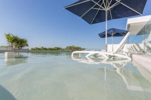 a swimming pool with an umbrella and a table and chairs at Downtown Condos Luxury in Playa del Carmen