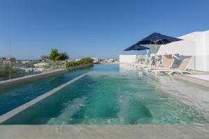 a swimming pool with chairs and an umbrella in the water at Downtown Condos Luxury in Playa del Carmen